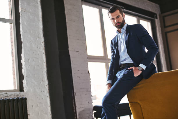 istock Confident young bearded brunet in elegant suit is looking at camera 1127483237