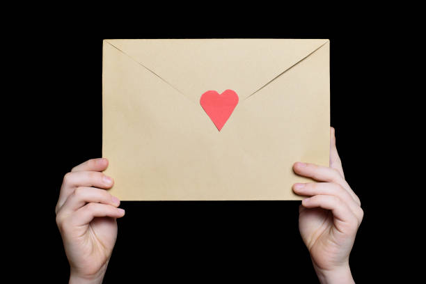 istock Children's hands hold an envelope with a heart shaped stamp. Isolate on black background. 1127483582