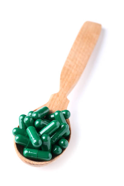 istock Spirulina capsules in wooden spoon isolated on white 1127484343