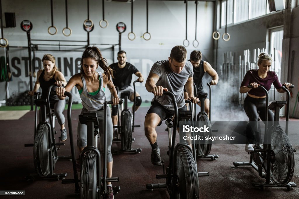 gym training on stationary bikes! Large group of athletic people having sports training on exercise bikes in a gym Gym Stock Photo