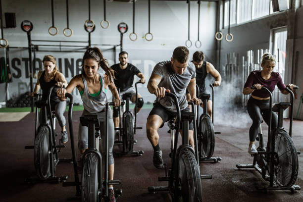 gym training on stationary bikes! Large group of athletic people having sports training on exercise bikes in a gym endurance stock pictures, royalty-free photos & images