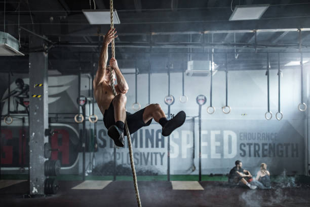 istock Young athletic man exercising strength on a rope in a gym. 1127486289