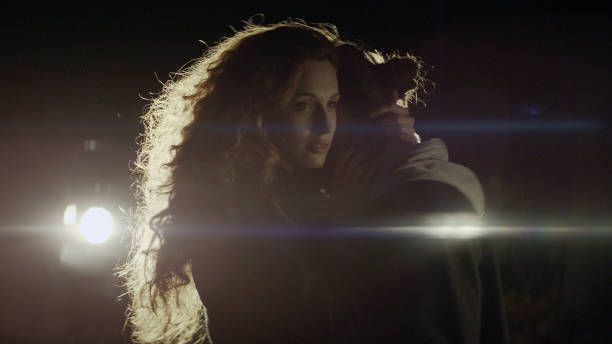 istock Couple standing in front of a car at night 1127487136