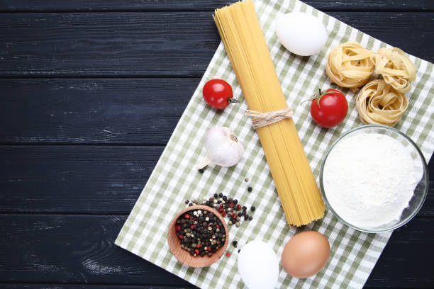 istock Different pasta with garlic, tomatoes, eggs and flour on wooden table 1127488058