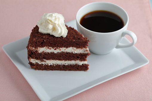Chocolate cake with cream and a cup of black coffee
