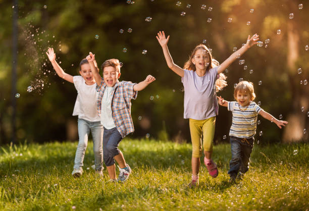 istock Happy kids with raised arms running among bubbles in springtime. 1127488974