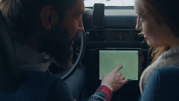 istock Cheerful young couple on road trip. Picking direction with tablet. 1127489301