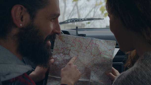 istock Cheerful young couple on road trip. Picking direction with map 1127489370