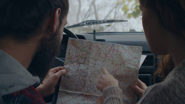 istock Cheerful young couple on road trip. Picking direction with map 1127489371