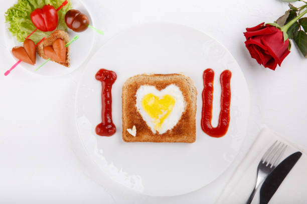istock Toasted bread with fried eggs within on white plate. Heart Eggs. Festive breakfast on white table. Happy Valentines day. Top view.  Copy space. 1127490821