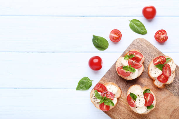 istock Bruschetta with mozzarella, tomatoes and basil leafs on wooden cutting board 1127492418
