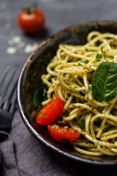 istock Close up pasta with pesto in bowl with cherry tomatoes at black background 1127493562