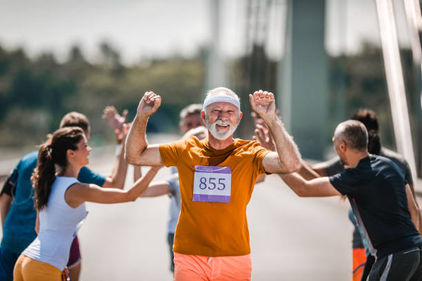 행복 한 수석 남자 마라톤 레이스의 끝을 축 하 하 그의 지지자를 통과 하는 동안. - marathon jogging success the end 뉴스 사진 이미지