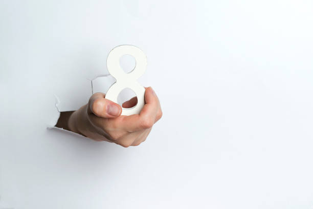 istock Female hand holding up the number eight a white background. 1127495324