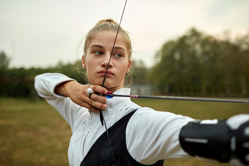 Teenage girl on archery training outdoors.