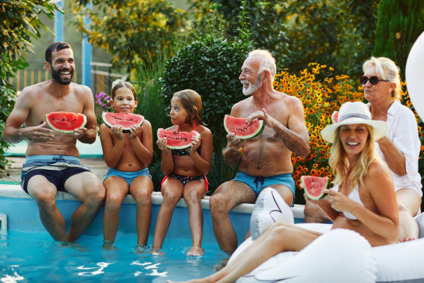 istock Multi generation Family Enjoy Watermelon Near Backyard Pool 1127497856