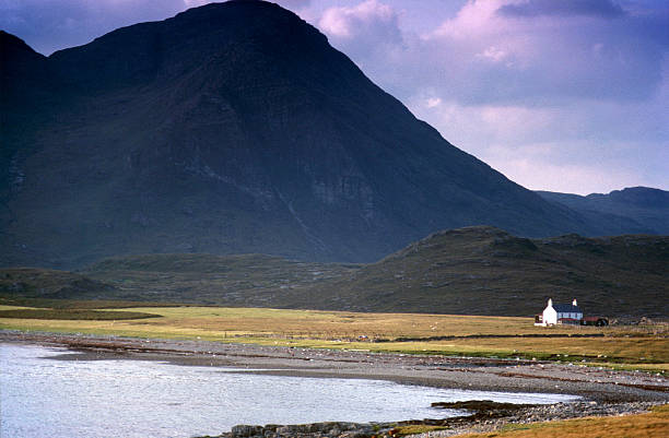 Wide angle view of small white cottage in the mountains of Glencoe, Scotland, UK