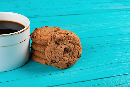cup of coffee and stack of sweet cookies on blue table