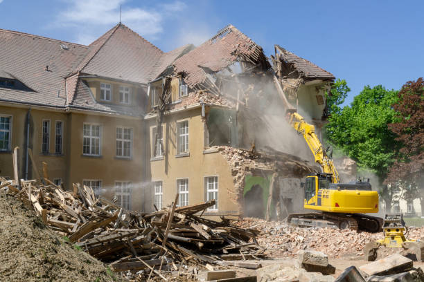 Demolition of old house. Excavator breaks building. City development, construction of new housing on site of old.