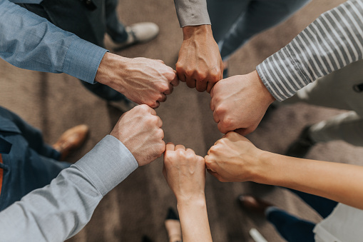 Above view of unrecognizable business team making a circle with their fists.