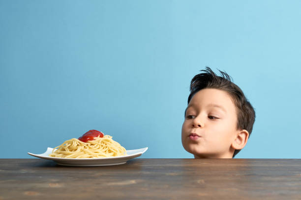 Child looking to spaghetti Child looking at spaghetti on plate from behind table kids eating noodles stock pictures, royalty-free photos & images