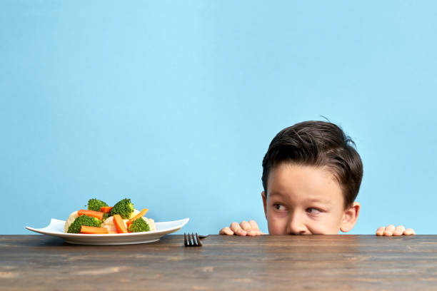 子供が野菜を食べることに非常に満足ではないです。 - cute disgust carrot caucasian ストックフォトと画像