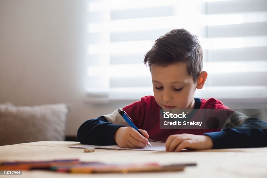 Junge zu Hause machen Hausaufgaben Schreiben von Briefen mit bunten Stiften - Lizenzfrei Porträt Stock-Foto