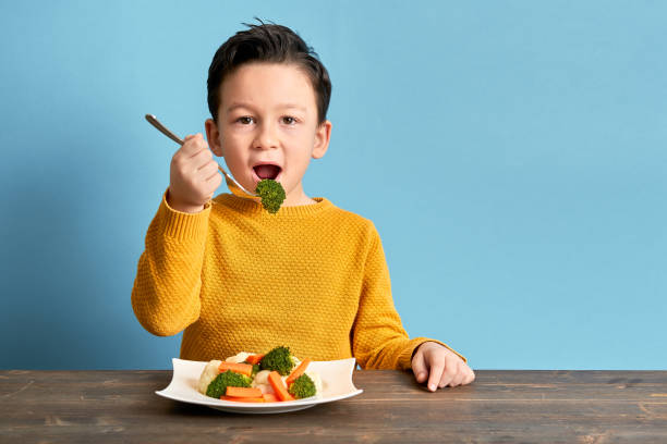 Child is eating vegetables. Child is eating vegetables. He is very happy. one boy only stock pictures, royalty-free photos & images