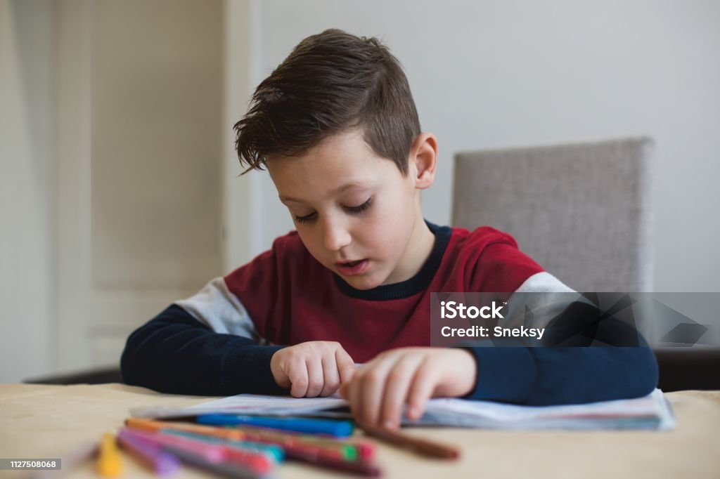 Junge zu Hause machen Hausaufgaben Schreiben von Briefen mit bunten Stiften - Lizenzfrei Akademisches Lernen Stock-Foto