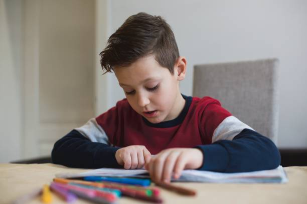 istock Boy at home making homework writing letters with colorful pens 1127508068