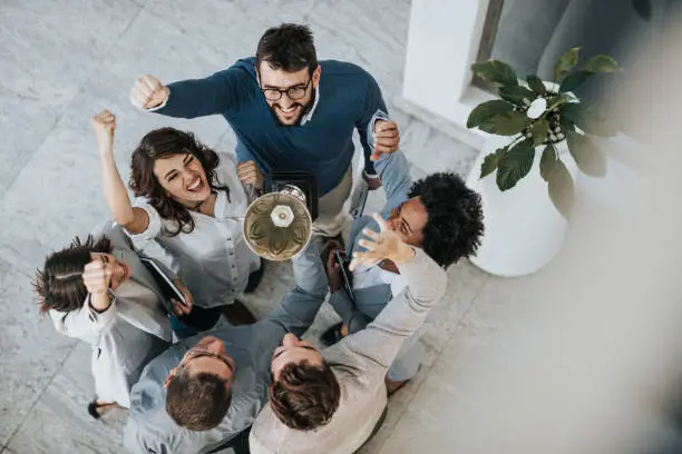 Above view of happy business team celebrating winning a trophy for their achievement.