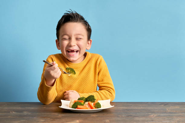 child is eating vegetables. - child eating imagens e fotografias de stock