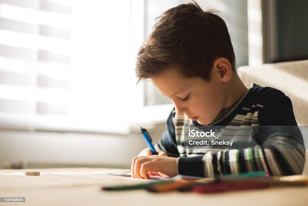Junge zu Hause machen Hausaufgaben Schreiben von Briefen mit bunten Stiften - Lizenzfrei Akademisches Lernen Stock-Foto