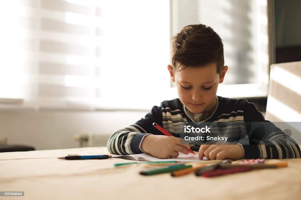 Junge zu Hause machen Hausaufgaben Schreiben von Briefen mit bunten Stiften - Lizenzfrei Akademisches Lernen Stock-Foto