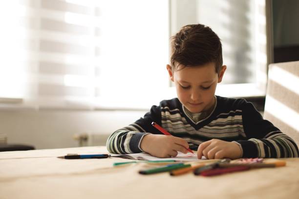 istock Boy at home making homework writing letters with colorful pens 1127508161
