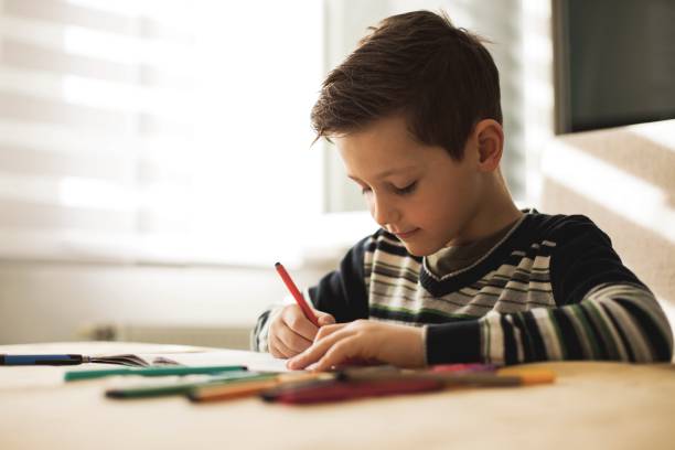 istock Boy at home making homework writing letters with colorful pens 1127508191