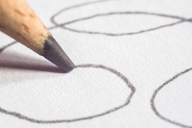A pencil draws on a sheet of white paper