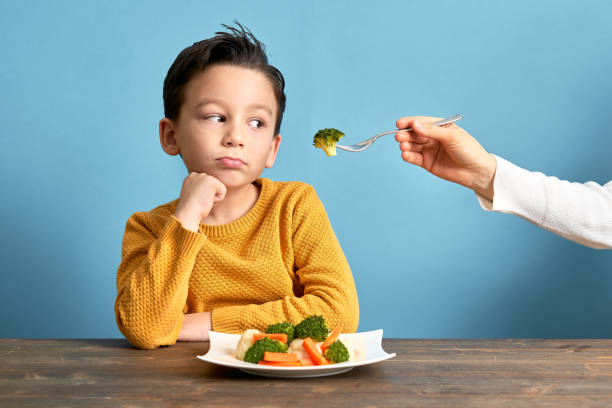 il bambino è molto infelice di dover mangiare verdure. - childrens food foto e immagini stock