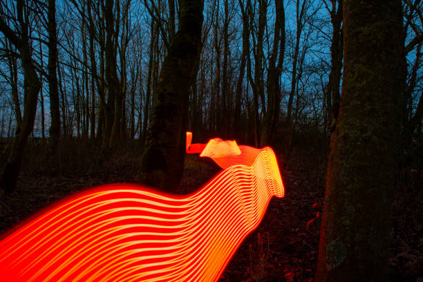 istock Red Neon light trails in a winter forest at dusk. 1127508300