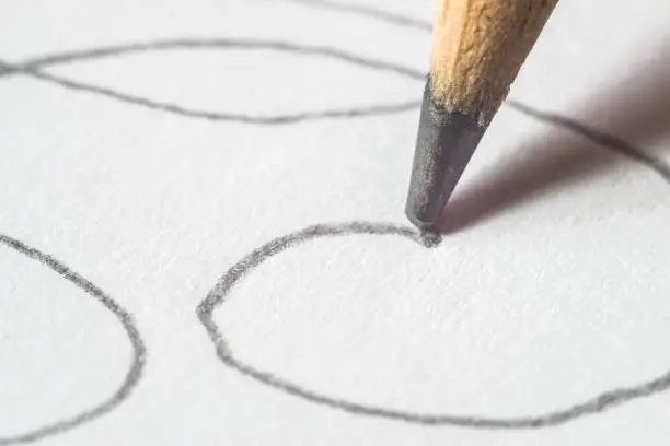 A pencil draws on a sheet of white paper