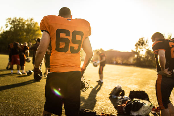 Rear view of American football players before game on sunlight