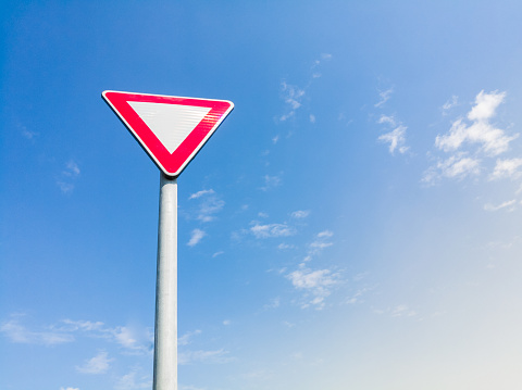 Un camino triangular da muestra de la manera de dar prioridad en un poste metálico con cielo azul como fondo photo
