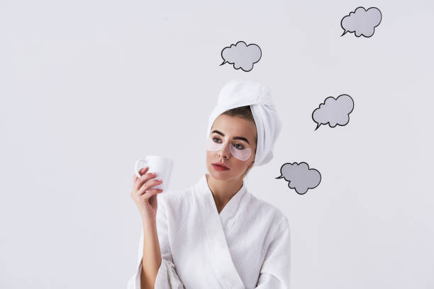 Portrait of beautiful girl surrounded by speech or thought bubbles. She is looking away with pensive expression while having cosmetic skin care procedure
