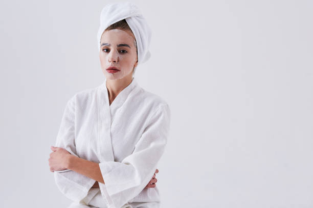 istock Young lady with purifying mask on her face standing against white background 1127513785