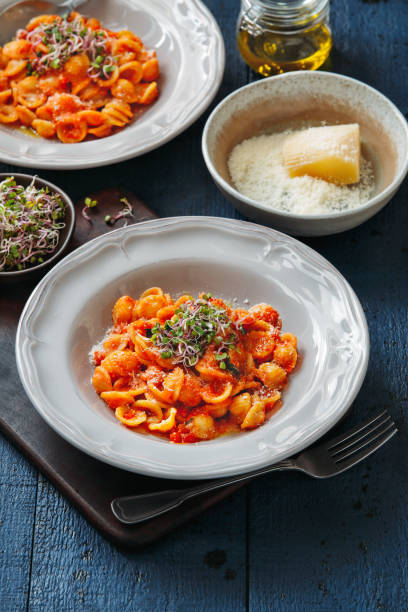 Orecchiette pasta with ricotta in tomato cream sauce Orecchiette pasta with ricotta in tomato cream sauce on dark blue background cooked selective focus vertical pasta stock pictures, royalty-free photos & images