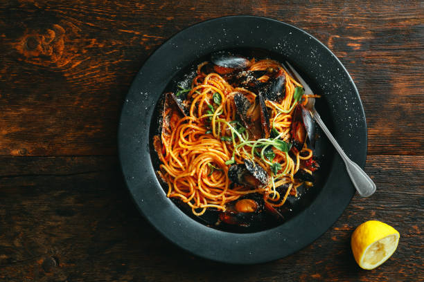 Spaghetti with smoky tomato & seafood sauce Spaghetti with smoky tomato & seafood sauce on dark blue background food styling stock pictures, royalty-free photos & images