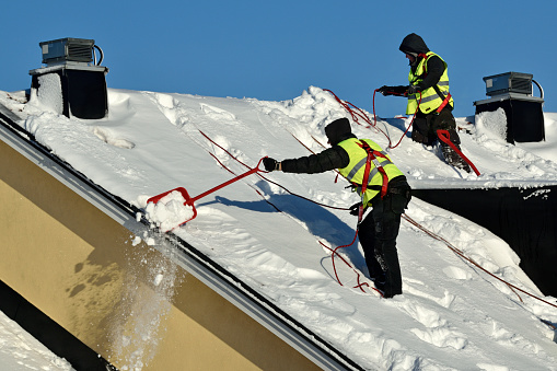 stockholm sweden 2019-01-05 unidentified Workers with snow shovels carry out winter cleaning of roof of building from snow and ice