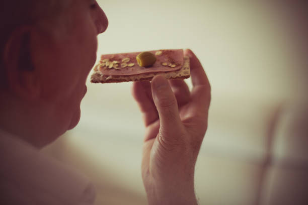 Healthy nutrition is important in late age. Senior man eating healthy meal. Close up. Copy space. Focus on hand.