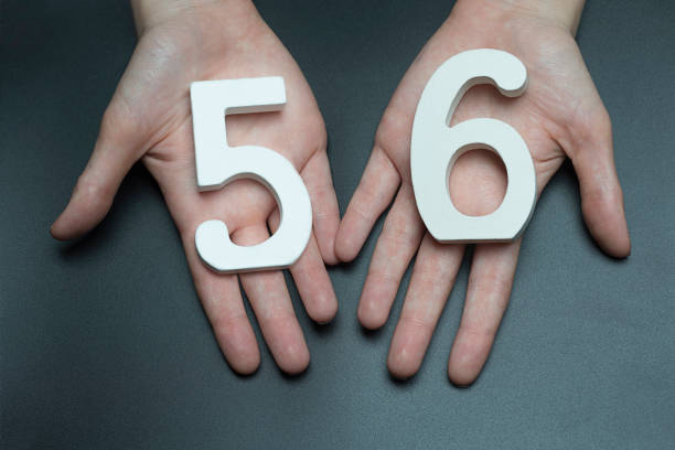 To female hands the number fifty-six. On a black background, female hand with number fifty-six. number 58 stock pictures, royalty-free photos & images