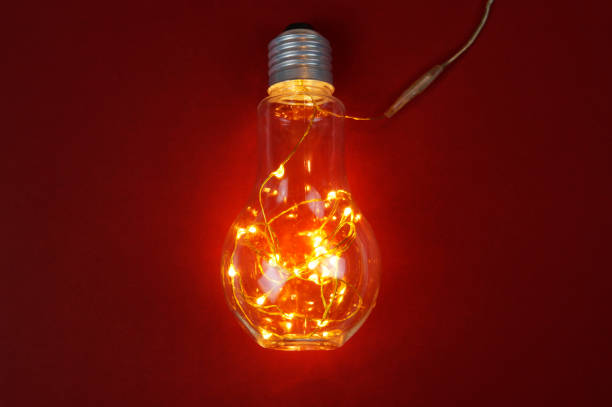 istock Light bulb with the glowing wire on a red background 1127519677
